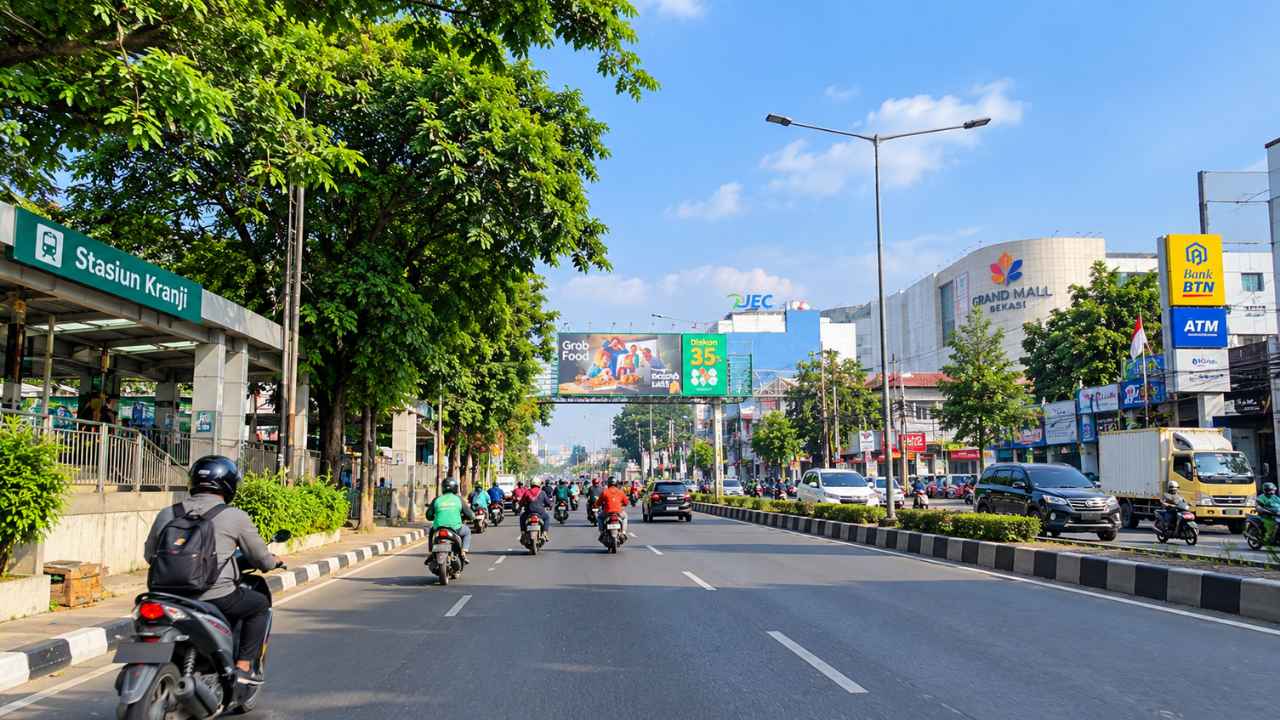 Daytime traffic on Jalan Jenderal Sudirman in Bekasi, with Stasiun Kranji on the left and the Grand Mall Bekasi and Bank BTN signs on the right